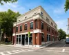 Brick-clad commercial building with a beige upper facade, multiple window units, and a corner street presence Brick-clad commercial building with a beige upper facade, multiple window units, and a corner street presence