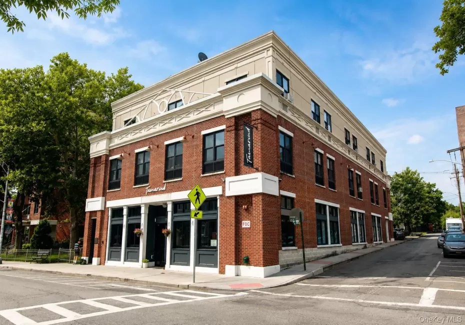Brick-clad commercial building with a beige upper facade, multiple window units, and a corner street presence Brick-clad commercial building with a beige upper facade, multiple window units, and a corner street presence