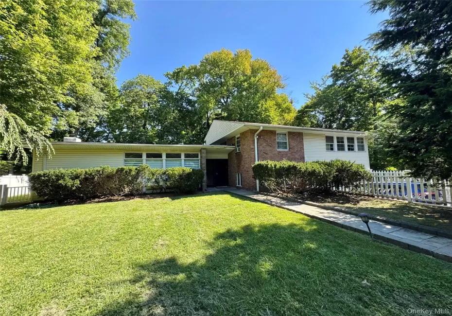 Split-level residence featuring a brick facade, white siding, and a prominent front lawn Split-level residence featuring a brick facade, white siding, and a prominent front lawn
