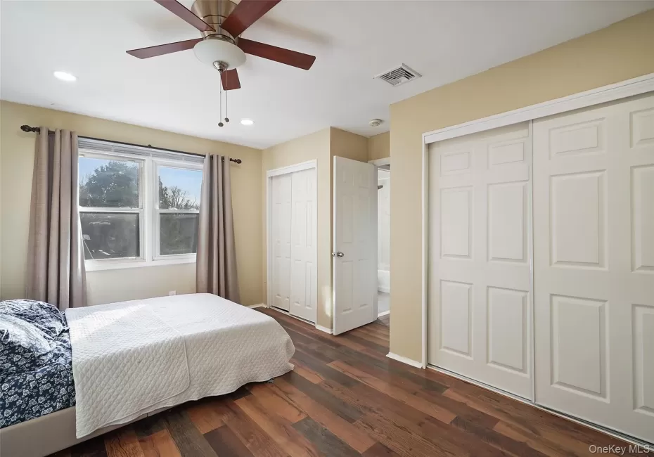 Bedroom with ceiling fan, dark hardwood / wood-style floors, and two closets Bedroom with ceiling fan, dark hardwood / wood-style floors, and two closets