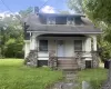 Exterior featuring a covered front porch with stone pillars, wood siding, and a gabled roofline Exterior featuring a covered front porch with stone pillars, wood siding, and a gabled roofline