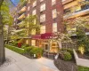 Brick exterior building featuring multiple balconies, a covered entrance, mature landscaping, and a well-maintained sidewalk Brick exterior building featuring multiple balconies, a covered entrance, mature landscaping, and a well-maintained sidewalk
