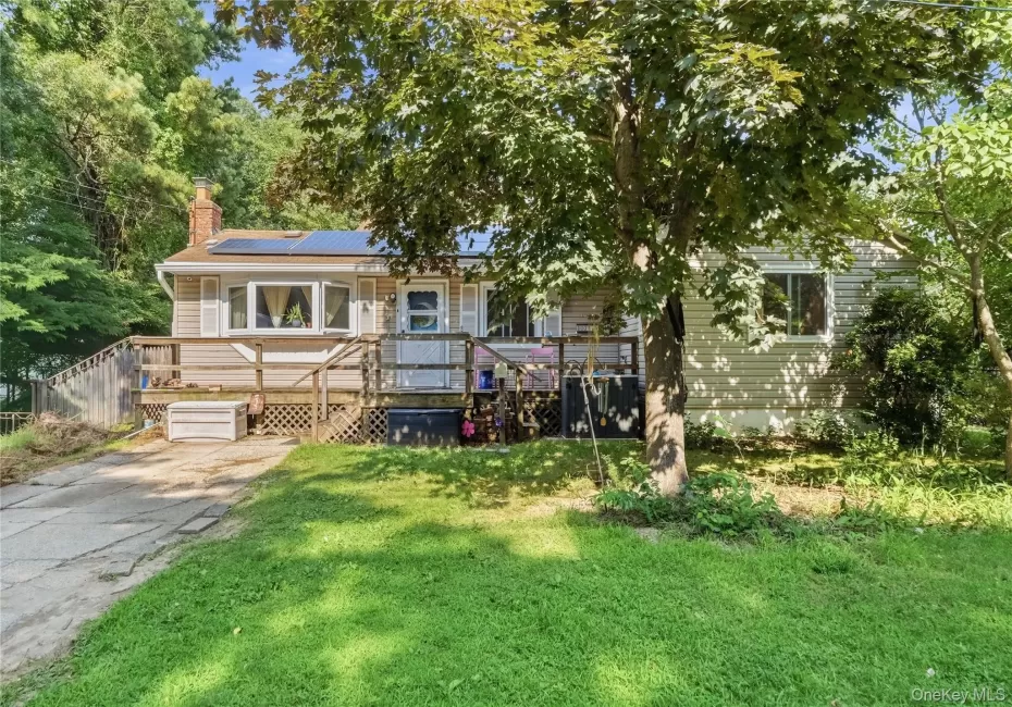 Siding exterior featuring a front deck with lattice skirting, bay window, and rooftop solar panels Siding exterior featuring a front deck with lattice skirting, bay window, and rooftop solar panels