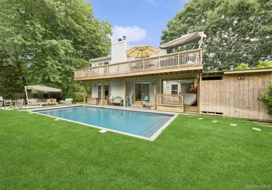 Back of house featuring a patio, a yard, a wooden deck, and a chimney Back of house featuring a patio, a yard, a wooden deck, and a chimney
