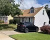 Cape cod home with a front lawn and a shingled roof Cape cod home with a front lawn and a shingled roof