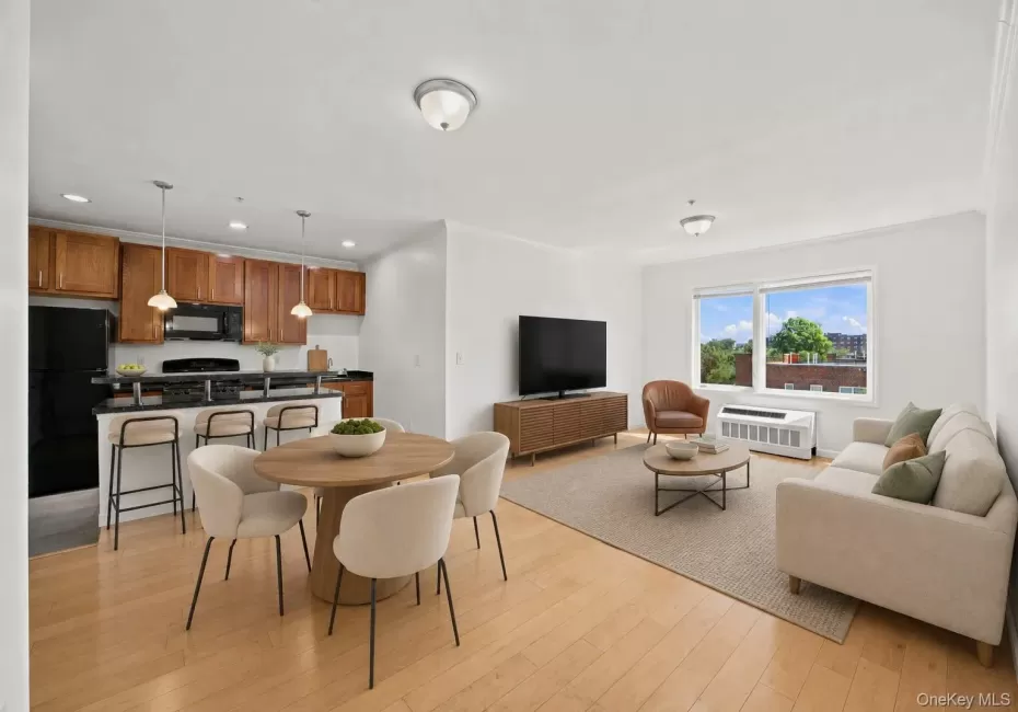 Open-concept living space featuring wood-finish flooring, a kitchen with wood cabinetry and black appliances, a dining area, and a living area with large windows Open-concept living space featuring wood-finish flooring, a kitchen with wood cabinetry and black appliances, a dining area, and a living area with large windows