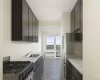 Galley kitchen featuring dark cabinetry with brushed metal hardware, gas cooktop with multiple burners, stainless steel sink, and quartz countertops Galley kitchen featuring dark cabinetry with brushed metal hardware, gas cooktop with multiple burners, stainless steel sink, and quartz countertops