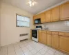 Kitchen with white gas range, light countertops, backsplash, radiator, and black microwave Kitchen with white gas range, light countertops, backsplash, radiator, and black microwave