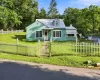 Turquoise siding with white trim and a white picket fence, and metal roof. Turquoise siding with white trim and a white picket fence, and metal roof.