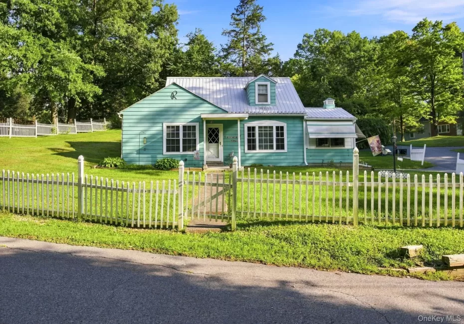 Turquoise siding with white trim and a white picket fence, and metal roof. Turquoise siding with white trim and a white picket fence, and metal roof.