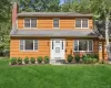 Wood shingle siding exterior with multiple windows, a prominent brick chimney, and a white paneled front door Wood shingle siding exterior with multiple windows, a prominent brick chimney, and a white paneled front door