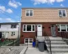 Brick facade with upper cedar shake siding, multiple white-framed windows, and a concrete entry staircase with black metal railings Brick facade with upper cedar shake siding, multiple white-framed windows, and a concrete entry staircase with black metal railings