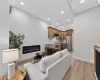 Open-concept living area featuring an electric fireplace, wood-finish flooring, recessed lighting, and a kitchen with wood cabinetry and stainless steel appliances Open-concept living area featuring an electric fireplace, wood-finish flooring, recessed lighting, and a kitchen with wood cabinetry and stainless steel appliances