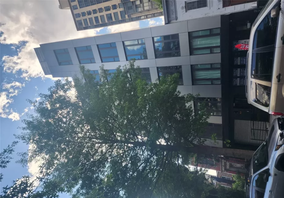 Modern multi-story building featuring a sleek facade, large windows, and a prominent treetop Modern multi-story building featuring a sleek facade, large windows, and a prominent treetop