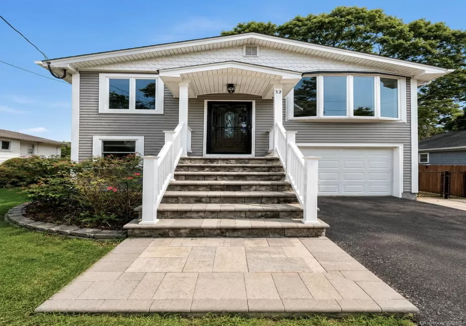 Exterior featuring gray siding, a covered entry porch, a bay window, and an attached garage with a white door. Exterior featuring gray siding, a covered entry porch, a bay window, and an attached garage with a white door.