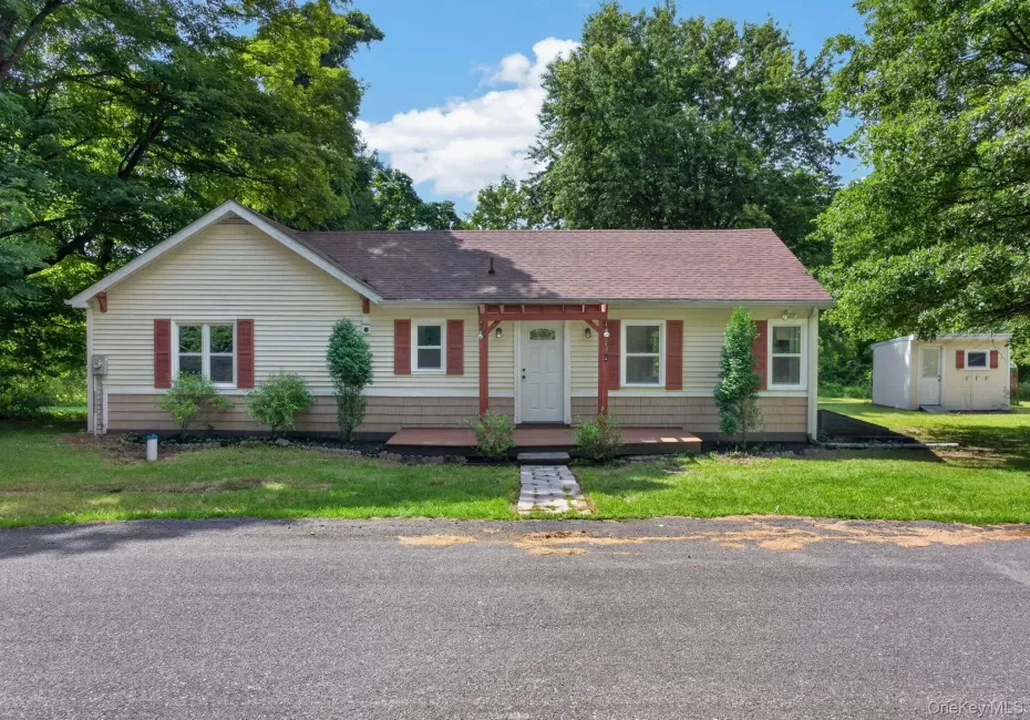 Cream vinyl siding exterior with red shutters, a covered entry, and a gravel walkway Cream vinyl siding exterior with red shutters, a covered entry, and a gravel walkway