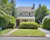American foursquare style home featuring a porch, a front yard, roof with shingles, and a chimney American foursquare style home featuring a porch, a front yard, roof with shingles, and a chimney