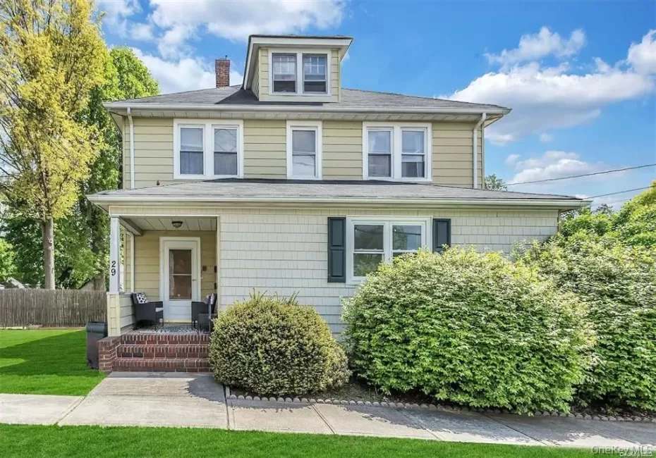 Two-story residence featuring dormer windows, a covered front porch with brick stairs, and horizontal and shingle siding Two-story residence featuring dormer windows, a covered front porch with brick stairs, and horizontal and shingle siding