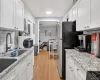 Kitchen with decorative backsplash, white cabinets, light stone counters, and black appliances Kitchen with decorative backsplash, white cabinets, light stone counters, and black appliances