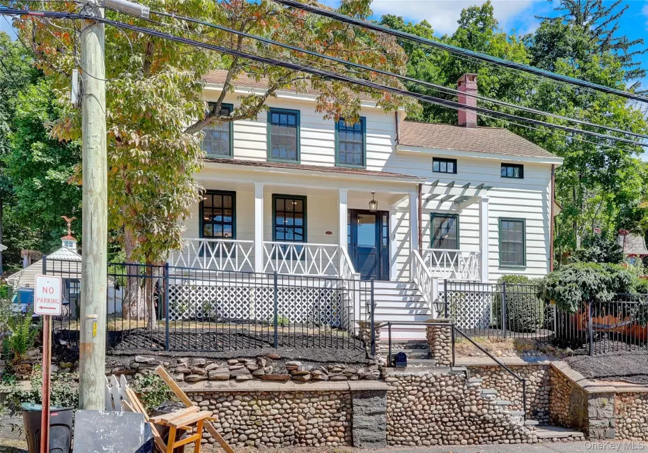 View of front of home featuring a chimney, a porch, stairway, and a shingled roof View of front of home featuring a chimney, a porch, stairway, and a shingled roof