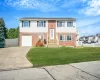 Raised ranch featuring driveway, brick siding, and a garage Raised ranch featuring driveway, brick siding, and a garage