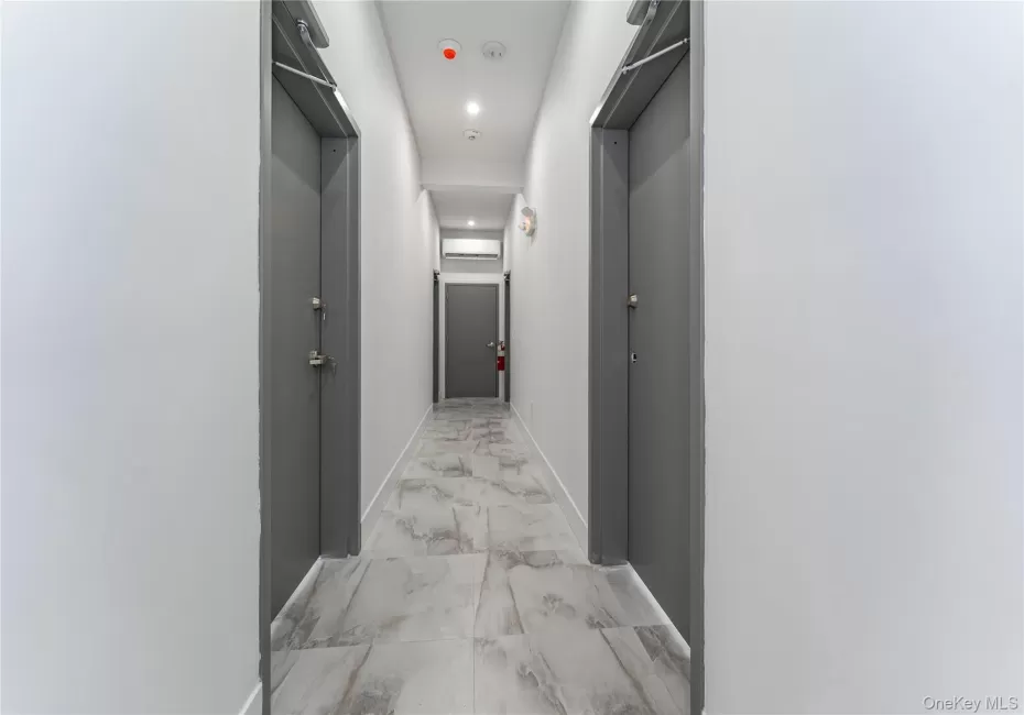 Corridor featuring light marble finish flooring, baseboards, and recessed lighting Corridor featuring light marble finish flooring, baseboards, and recessed lighting
