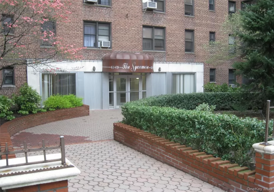 Brick facade building featuring a curved entrance awning, and a paved entry path Brick facade building featuring a curved entrance awning, and a paved entry path