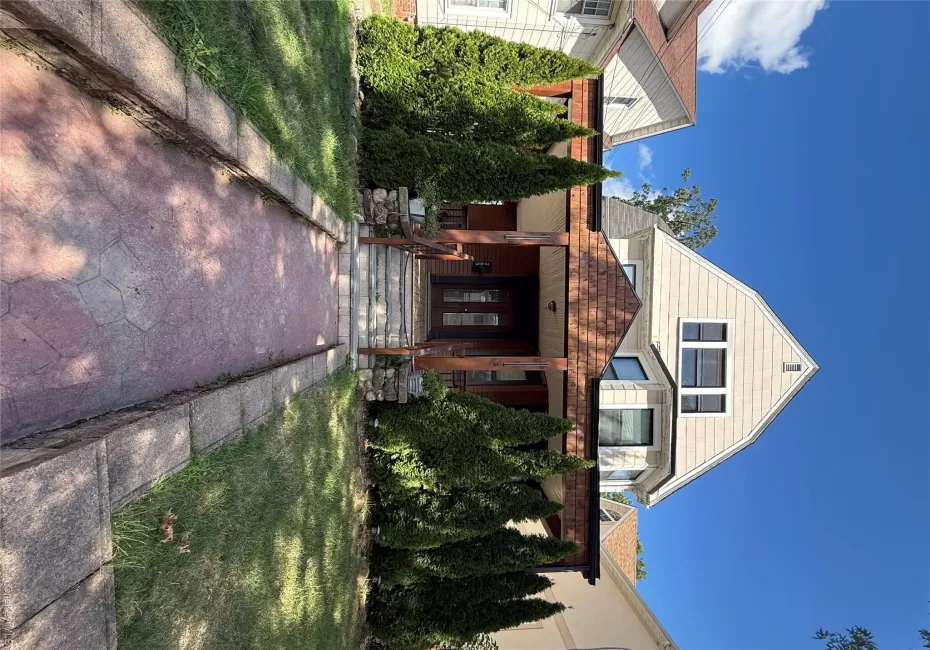 Gabled exterior with light-colored siding, a covered entry porch, patterned shingle roofing, and a stone-lined walkway Gabled exterior with light-colored siding, a covered entry porch, patterned shingle roofing, and a stone-lined walkway