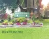 Manicured landscaping with a stone-clad raised planter, a variety of colorful flowering plants, and mature trees Manicured landscaping with a stone-clad raised planter, a variety of colorful flowering plants, and mature trees