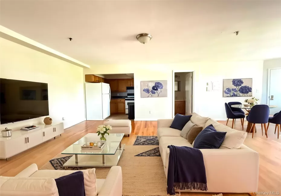 Open-concept living space featuring wood-finish flooring, recessed lighting, and a dining area with a glass-top table Open-concept living space featuring wood-finish flooring, recessed lighting, and a dining area with a glass-top table