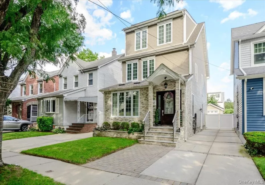 Stone facade with an inviting covered entryway, prominent front windows, and a paved driveway leading to a private rear gate Stone facade with an inviting covered entryway, prominent front windows, and a paved driveway leading to a private rear gate