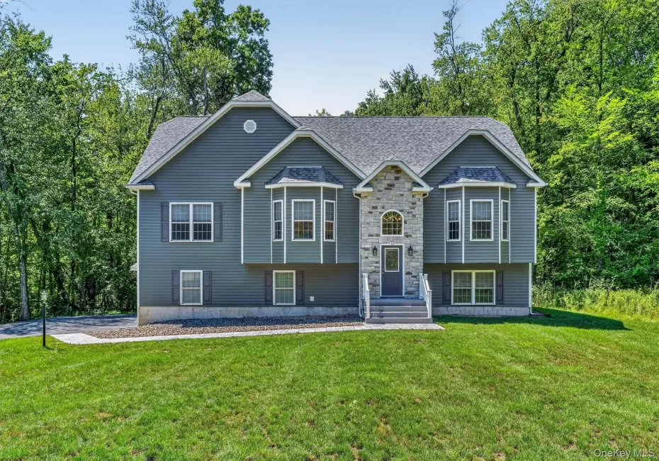 Exterior featuring stone and siding finishes, multiple bay windows, a gabled roofline, and a manicured lawn Exterior featuring stone and siding finishes, multiple bay windows, a gabled roofline, and a manicured lawn