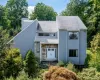 Contemporary exterior featuring vertical siding, a stone facade entry, a gabled roofline, and ample natural landscaping Contemporary exterior featuring vertical siding, a stone facade entry, a gabled roofline, and ample natural landscaping