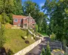 Red brick exterior with white trim, prominent stone chimney, and a covered entry Red brick exterior with white trim, prominent stone chimney, and a covered entry