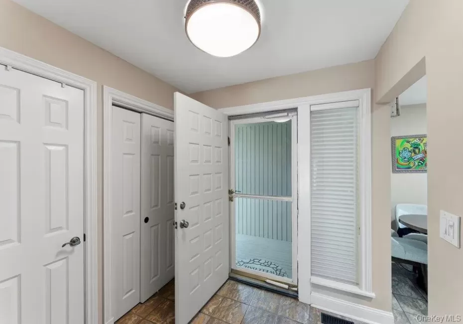 Entry way featuring tiled flooring, a flush-mount ceiling light, white paneled doors, and a front entry door with an adjacent window Entry way featuring tiled flooring, a flush-mount ceiling light, white paneled doors, and a front entry door with an adjacent window