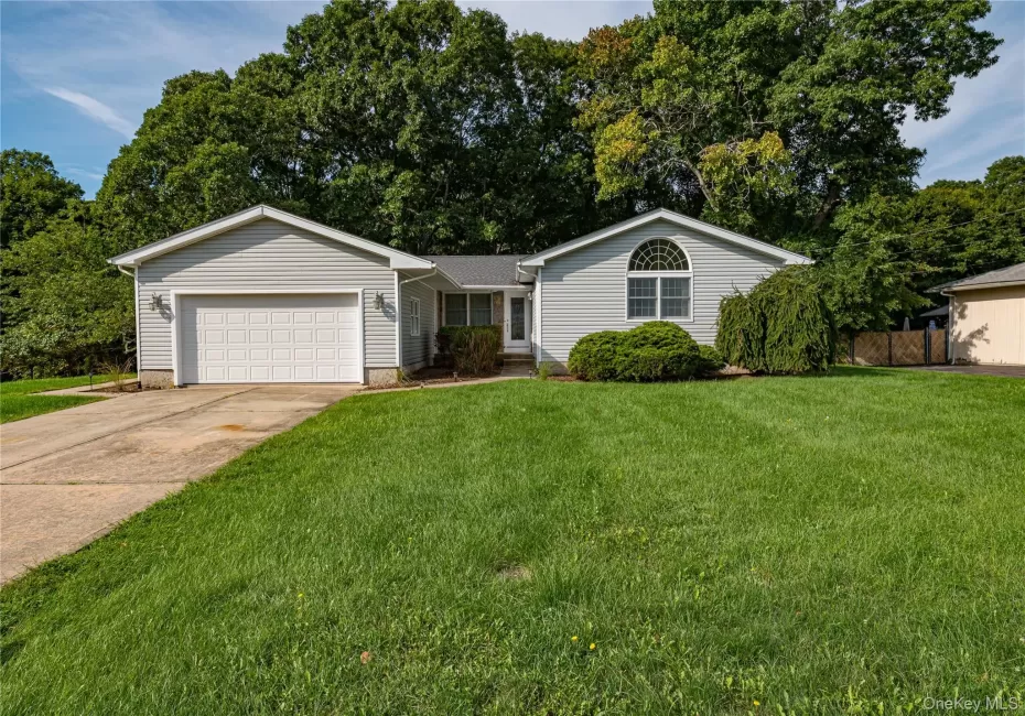Grey vinyl siding exterior with a concrete driveway, attached garage, and a semicircular arched window Grey vinyl siding exterior with a concrete driveway, attached garage, and a semicircular arched window