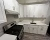 Kitchen with dark hardwood / wood-style flooring, stainless steel gas stove, white cabinets, and sink Kitchen with dark hardwood / wood-style flooring, stainless steel gas stove, white cabinets, and sink