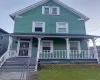 Two-story residence with a covered front porch, white railing, and exterior lighting Two-story residence with a covered front porch, white railing, and exterior lighting