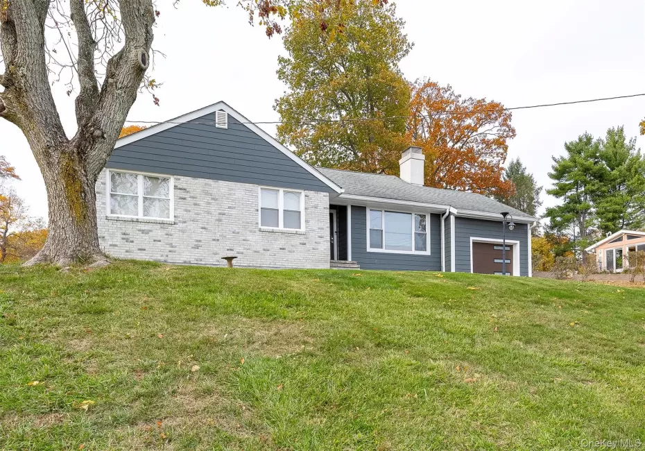 View of front facade featuring a front lawn, a garage, a chimney, and brick siding View of front facade featuring a front lawn, a garage, a chimney, and brick siding
