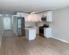 Beautifully renovated kitchen with appliances with stainless steel finishes, decorative backsplash, white cabinetry, a kitchen island, and light wood like floors Beautifully renovated kitchen with appliances with stainless steel finishes, decorative backsplash, white cabinetry, a kitchen island, and light wood like floors