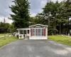 White siding exterior featuring a sunroom, bay window with red shutters, and an asphalt driveway. White siding exterior featuring a sunroom, bay window with red shutters, and an asphalt driveway.