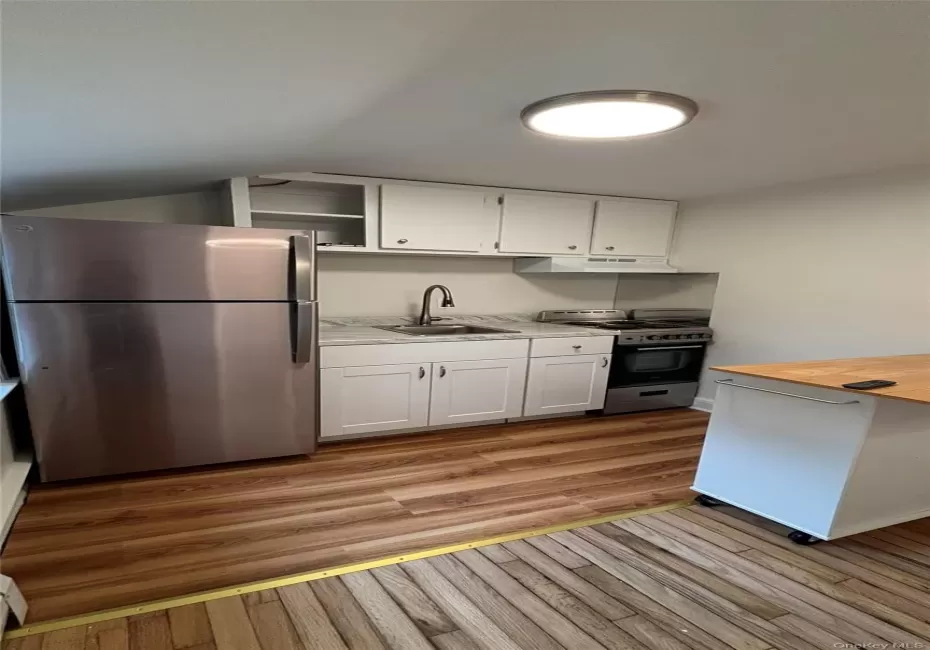 Kitchen with stainless steel appliances, under cabinet range hood, white cabinets, and light wood finished floors Kitchen with stainless steel appliances, under cabinet range hood, white cabinets, and light wood finished floors