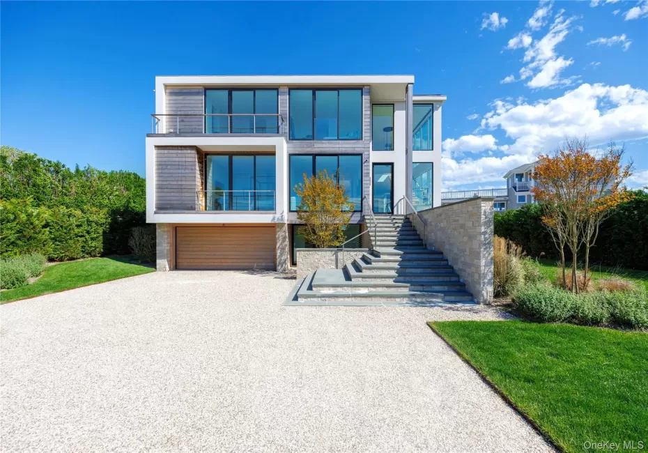 Modern home featuring driveway, an attached garage, stairs, and a front yard Modern home featuring driveway, an attached garage, stairs, and a front yard