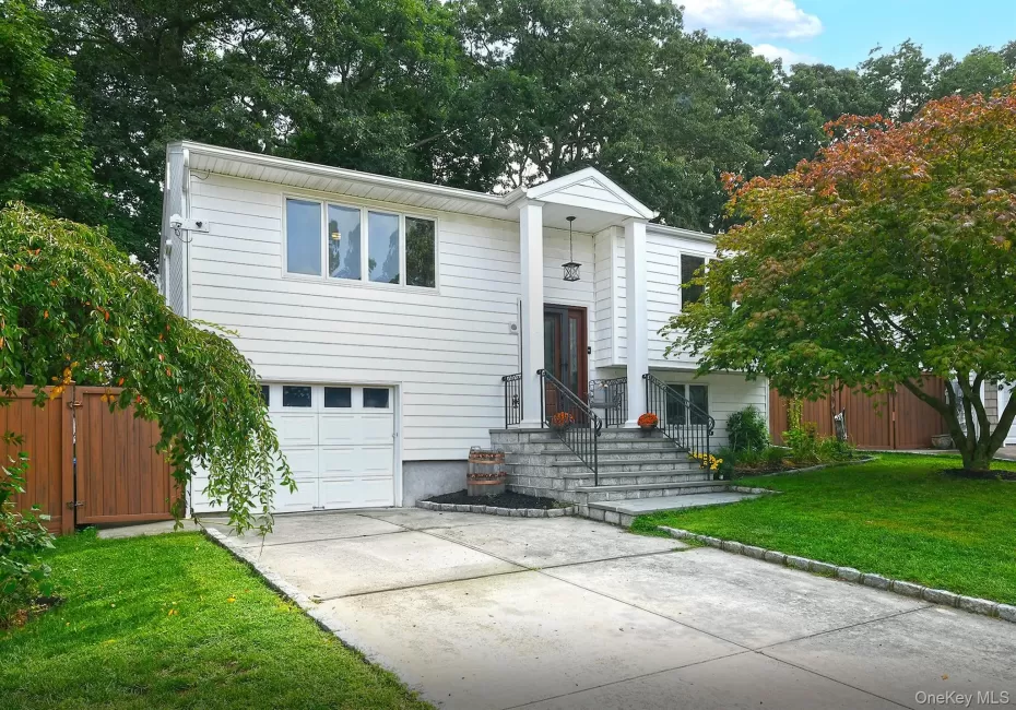 White siding exterior with a prominent covered entry, stone steps, and an attached garage with a white door White siding exterior with a prominent covered entry, stone steps, and an attached garage with a white door