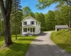 Two-story white residence featuring a covered front porch, black window shutters, and a grey asphalt driveway Two-story white residence featuring a covered front porch, black window shutters, and a grey asphalt driveway