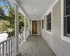 Covered porch with wood flooring, classic columns, a paneled wood entry door, and plank siding Covered porch with wood flooring, classic columns, a paneled wood entry door, and plank siding