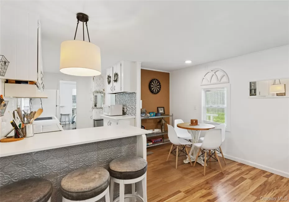 Kitchen with white cabinets, tasteful backsplash, hanging light fixtures, a peninsula, and light countertops Kitchen with white cabinets, tasteful backsplash, hanging light fixtures, a peninsula, and light countertops