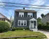 Two-story residence featuring shingle siding, a front porch with an awning, and a manicured lawn Two-story residence featuring shingle siding, a front porch with an awning, and a manicured lawn