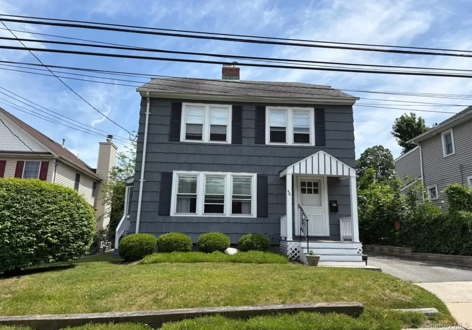 Two-story residence featuring shingle siding, a front porch with an awning, and a manicured lawn Two-story residence featuring shingle siding, a front porch with an awning, and a manicured lawn