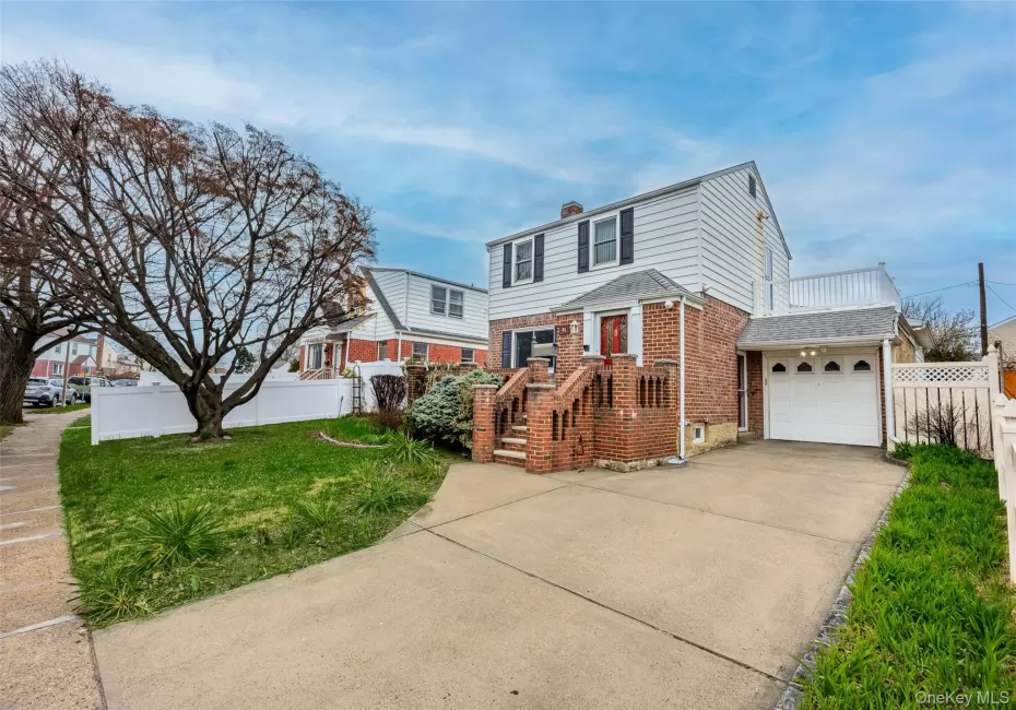 The property features a driveway, an attached garage, and a front lawn with a mature tree The property features a driveway, an attached garage, and a front lawn with a mature tree